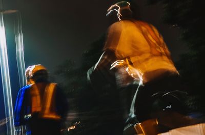 Rear view of people standing against illuminated fire at night