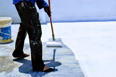 Low section of painter painting floor with paint roller