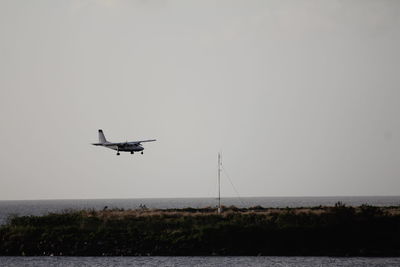 Airplane flying over sea against clear sky