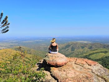 Rear view of woman sitting on rock