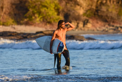 Full length of man with surfboard standing at beach