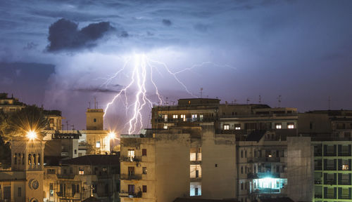 Lightning over buildings against sky at night