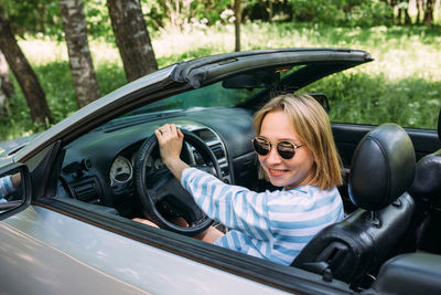 A woman is driving a convertible car. summer road trip to nature