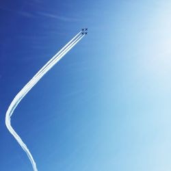 Low angle view of airplanes flying in blue sky