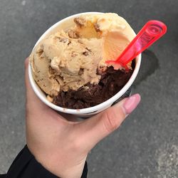 Close-up of woman hand holding ice cream in cup on street
