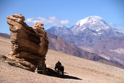People riding motorcycle on snowcapped mountain against sky