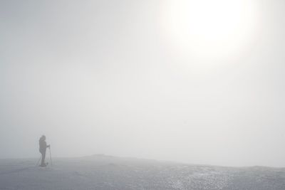 Rear view of man standing on mountain against sky