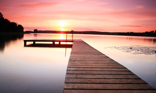 Pier over lake against sky during sunset