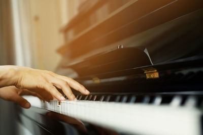 Cropped hand of woman playing piano