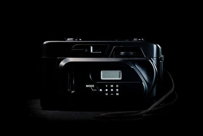 Close-up of camera on table against black background