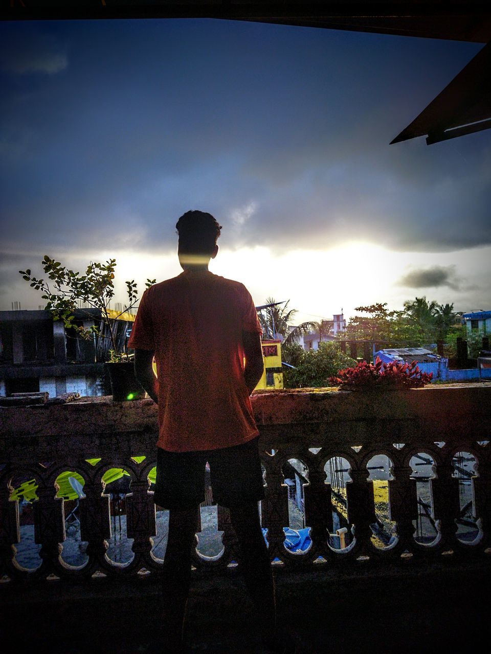 REAR VIEW OF MAN STANDING BY BOTTLES AGAINST SKY