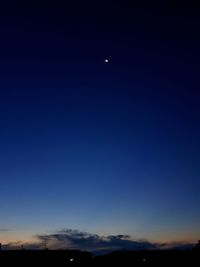 Silhouette landscape against clear blue sky at night