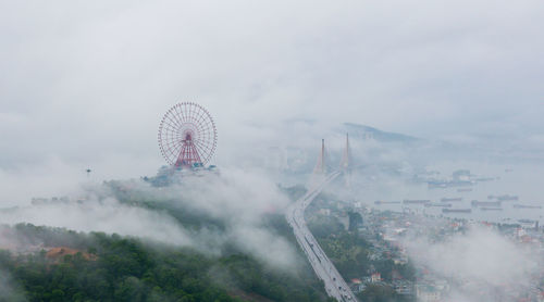 Aerial view of ferris wheel in city during foggy weather