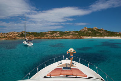 Rear view of woman on yacht boat deck in aegean sea against sky