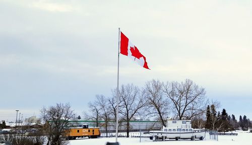 Flag on snow covered landscape against sky