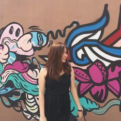 Woman standing against graffiti wall