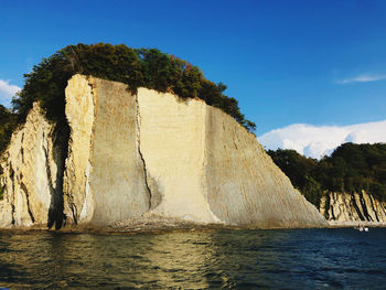 Rock formation in sea against blue sky