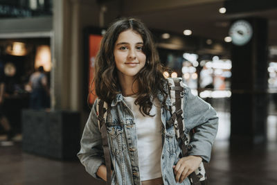 Portrait of smiling girl wearing denim jacket while standing at station