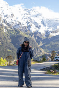An indian woman posing in snow suit in front of snowy mountain of himalayas