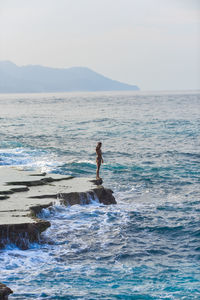 Rear view of man standing on sea against sky