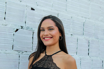 Portrait of smiling young woman against wall