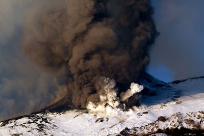 Smoke emitting from volcanic mountain against sky