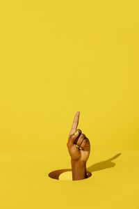 Close-up of woman hand against yellow background