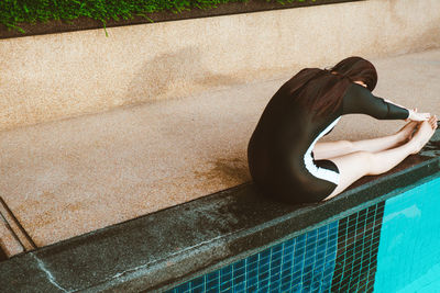 Woman sitting by swimming pool