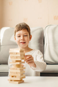 A smiling caucasian boy plays at home, on the table in jenga. board games for children and adults. 