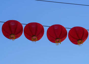 Low angle view of lanterns hanging against clear blue sky