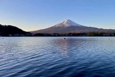 Scenic view of lake and mountains against clear blue sky