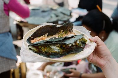 Cropped image of woman holding plate with blue corn quesadillas