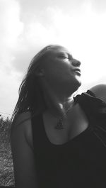 Portrait of young woman looking away against sky