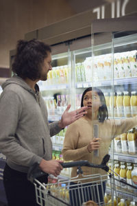 Couple standing in supermarket and talking while shopping