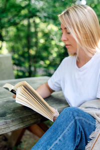 A young woman reads a book outdoors.