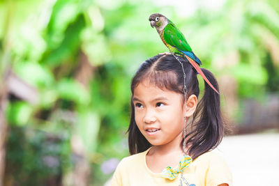 Cute girl looking away with bird on head