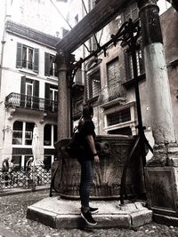 Full length of woman standing on street amidst buildings