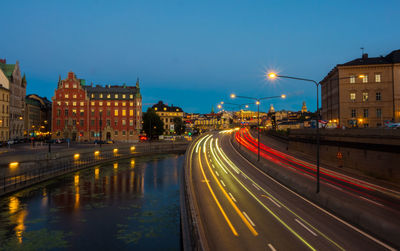 Light trails on city street by buildings at night