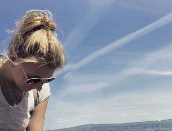 Young woman with sunglasses on beach against sky