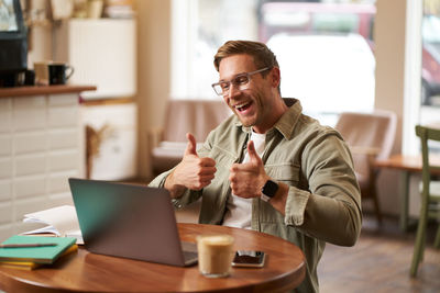 Side view of young man using laptop at office