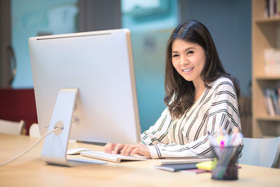 Portrait of woman using mobile phone while sitting on table