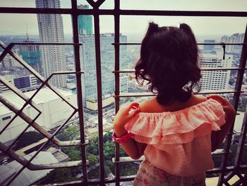 Rear view of girl standing against railing