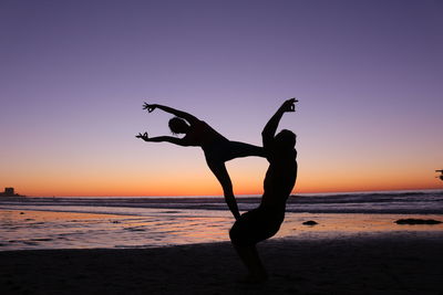 Silhouette man on beach against clear sky during sunset