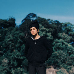 Teenage boy with eyes closed standing against trees