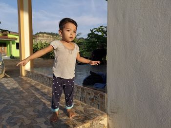 Portrait of girl with arms outstretched standing on tiled floor