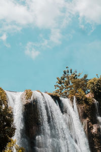 Low angle view of waterfall against sky