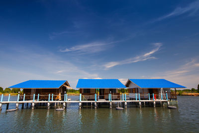 Built structure by lake against blue sky