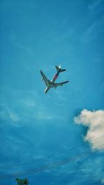 Low angle view of airplane flying against blue sky