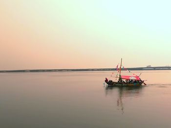 Fishing boat in sea against sky during sunset