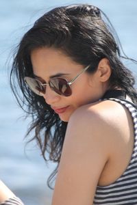Close-up of woman wearing sunglasses sitting against sea